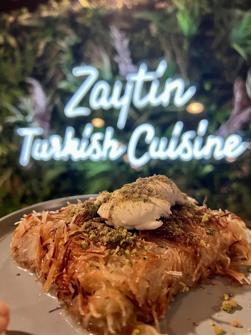 Neon Zaytin tabelasının önünde kaymaklı künefe