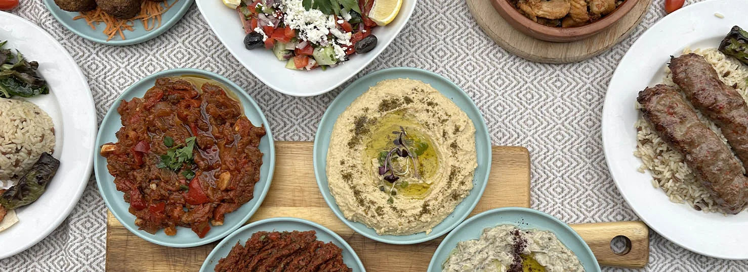 Zaytin sofrasında kuşbakışı mezeler, salatalar ve kebap tabakları
